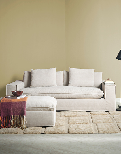 Beige soffa med fotpall i gult rum