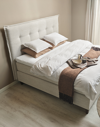 Beige kontinentalsäng med sänggavel