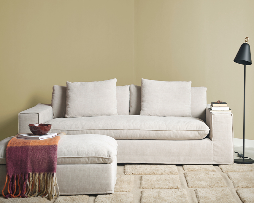 Beige soffa med pall i ett gult rum