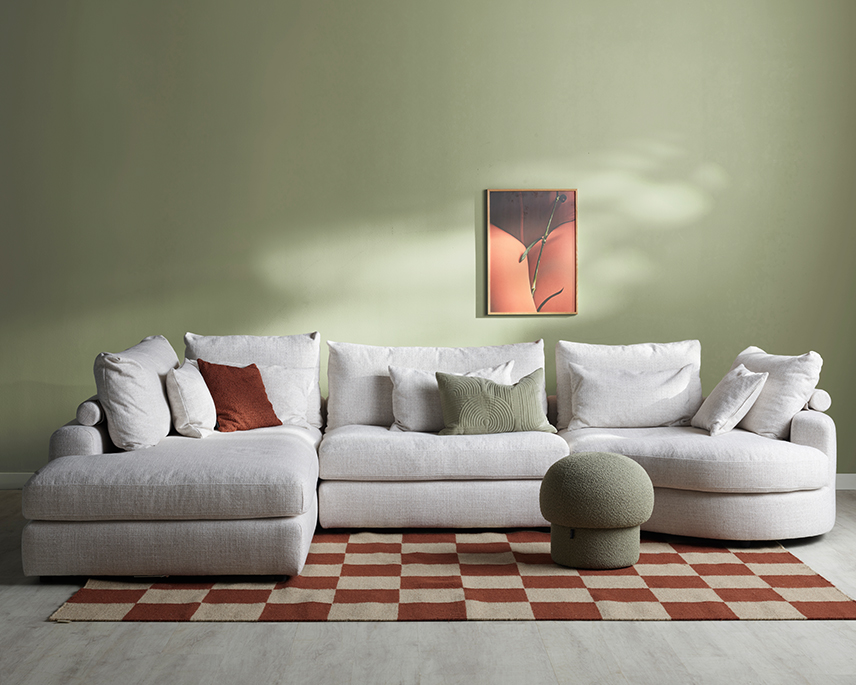 Beige hörnsoffa med öppet avslut, i ett grönt rum