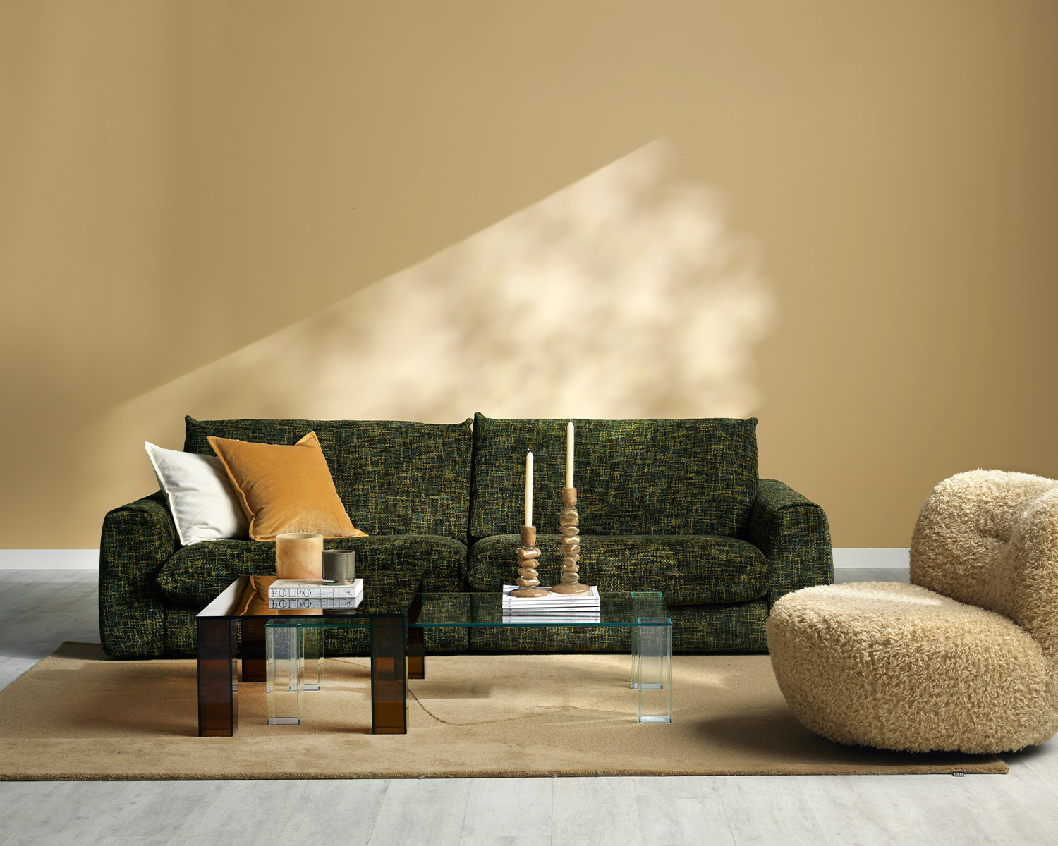 Grön soffa i gult rum med glasbord och fårskinnsfåtölj