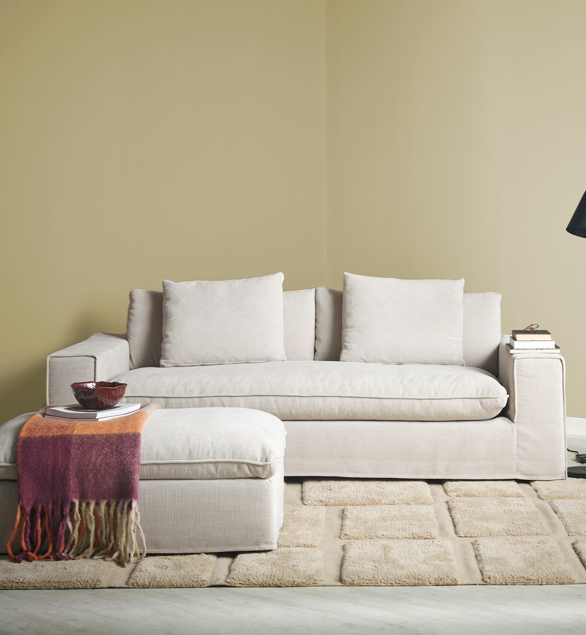 Beige soffa med pall i ett gult rum