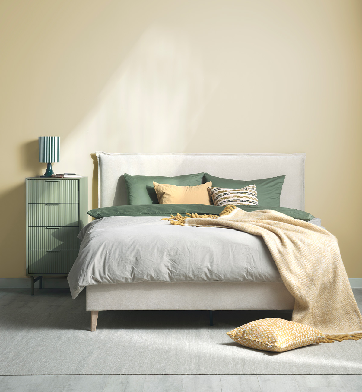 Beige säng med gavel i ett gult rum