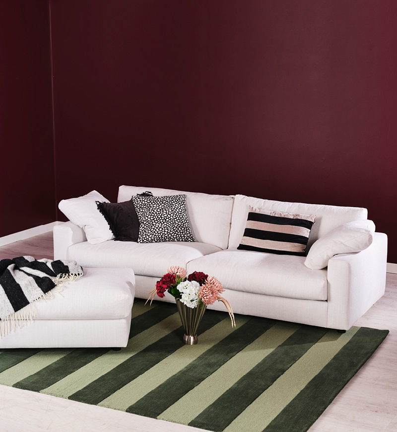 Vit soffa i ett burgundy rum med randiga detaljer