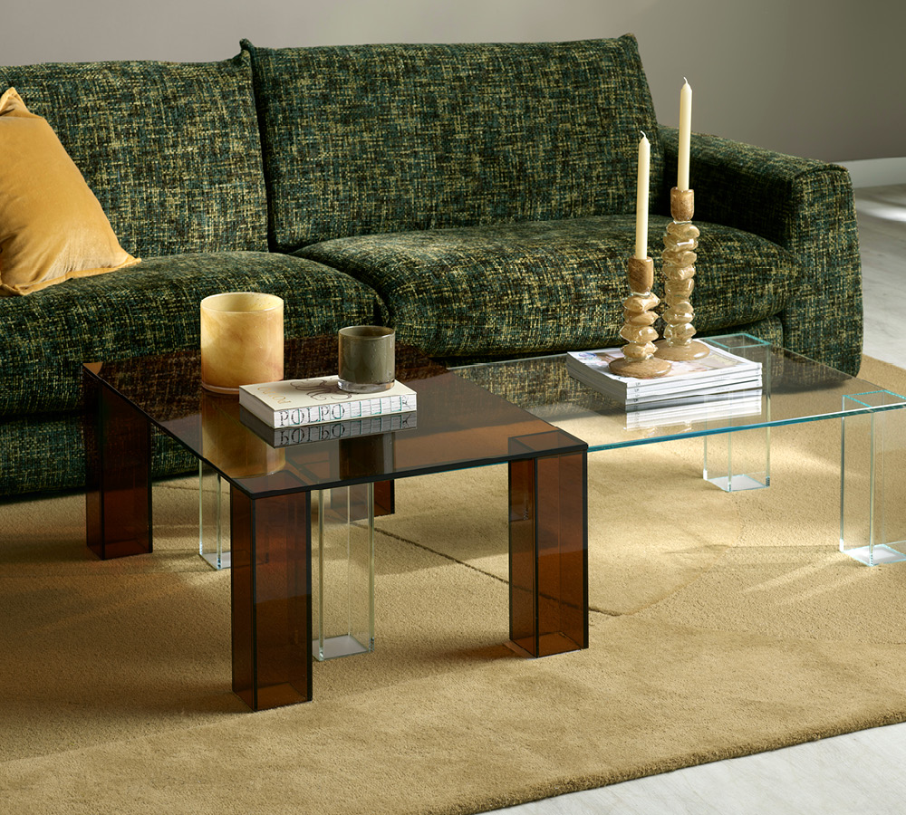 Brunt glasbord framför en grön soffa