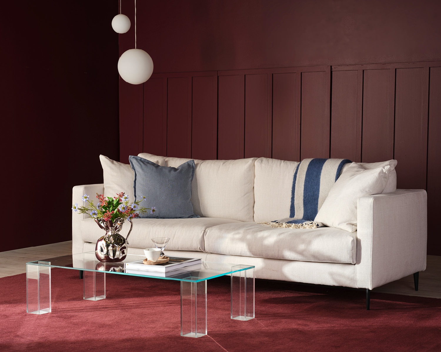 beige soffa i ett rött rum med glasbord