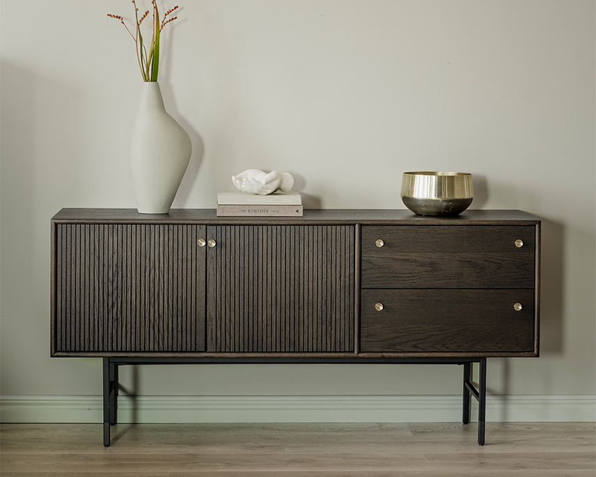 Brunt sideboard med guldknoppar i grönt rum